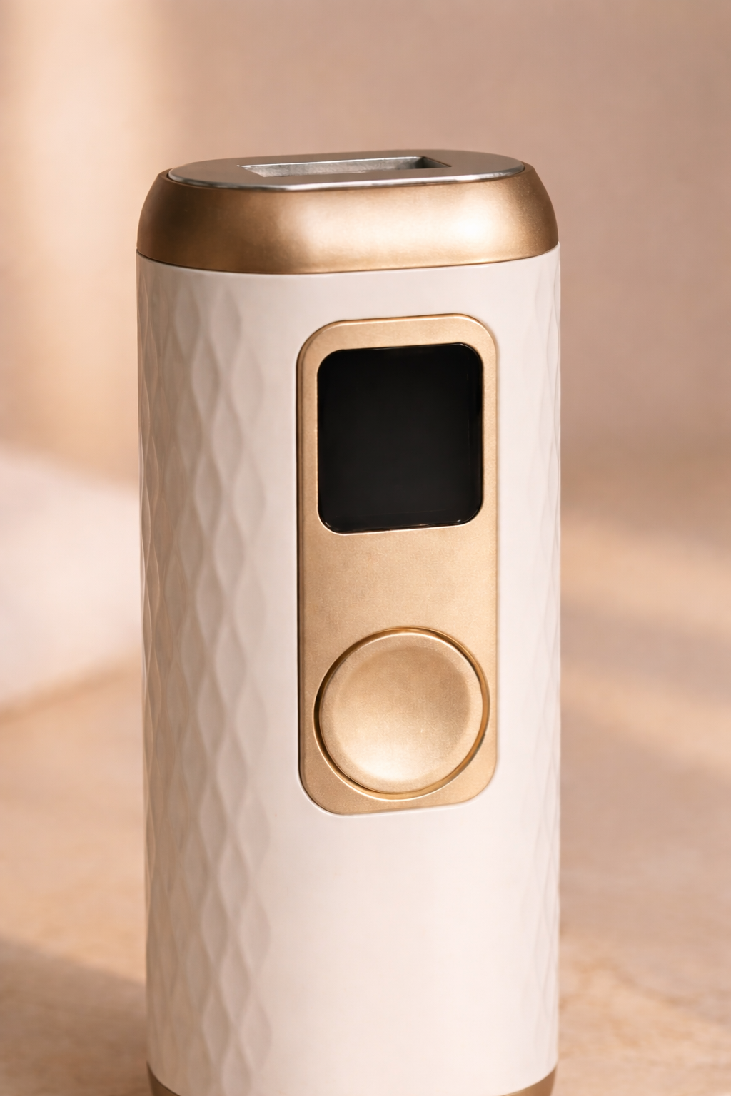 Close-up view of a premium white and gold hair removal device showing control button and display with elegant textured design.